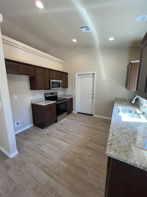 3521 E Lum Ave, Kingman, AZ 86409 - kitchen with stainless steel appliances, a sink, baseboards, dark brown cabinets, and vaulted ceiling