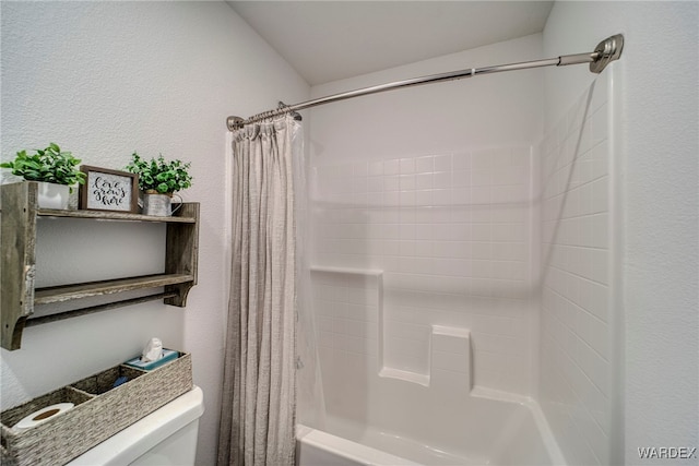 bathroom featuring shower / bath combo, a textured wall, and toilet