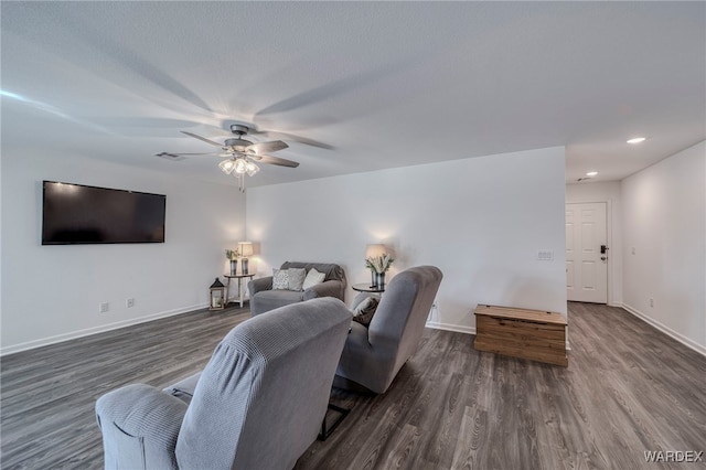 living room featuring ceiling fan, visible vents, baseboards, and dark wood-style flooring