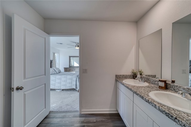 full bath featuring double vanity, connected bathroom, a sink, and wood finished floors