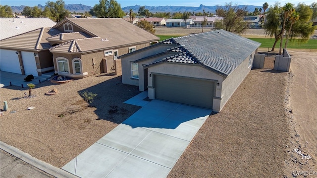 view of front facade with driveway, a tile roof, a residential view, and a mountain view