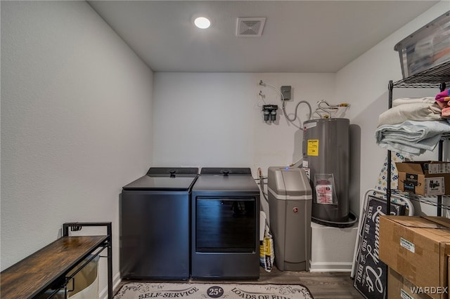 laundry area with laundry area, dark wood-type flooring, visible vents, water heater, and washer and clothes dryer