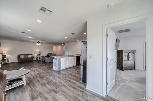 living area with a ceiling fan, light wood-type flooring, visible vents, and baseboards