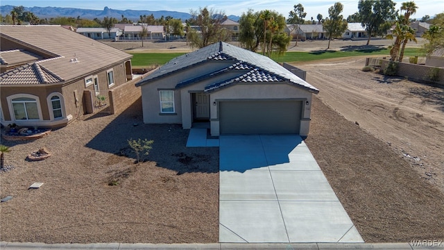 view of front facade featuring driveway, a residential view, an attached garage, a mountain view, and stucco siding