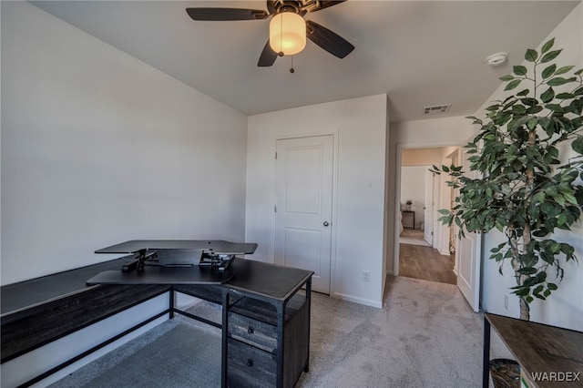 office space with ceiling fan, visible vents, baseboards, and light colored carpet