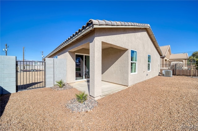 back of property featuring a patio, fence, a tiled roof, a gate, and stucco siding