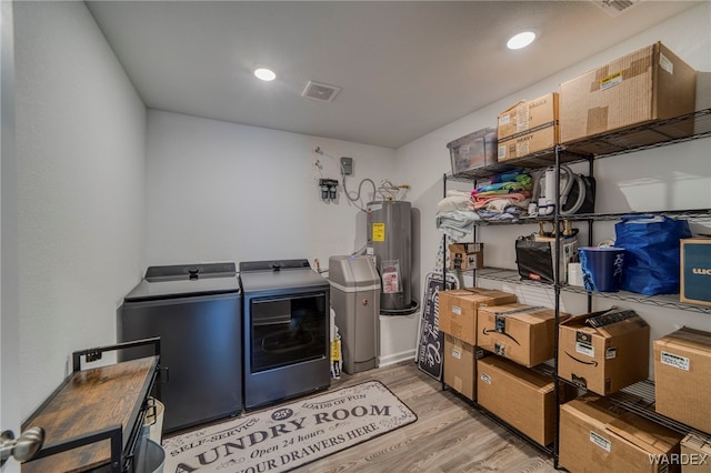 laundry area with laundry area, visible vents, light wood-style floors, water heater, and separate washer and dryer