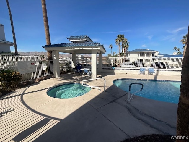 pool with a community hot tub, a patio, a gazebo, and fence