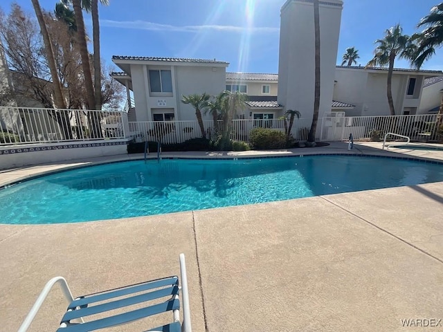 community pool with a patio and fence