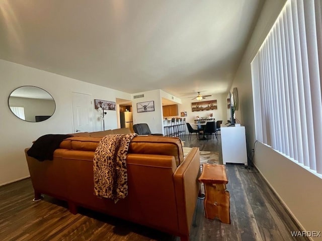 living room featuring dark wood-type flooring, visible vents, and ceiling fan