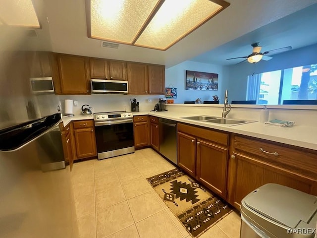 kitchen featuring appliances with stainless steel finishes, brown cabinets, light countertops, and a sink