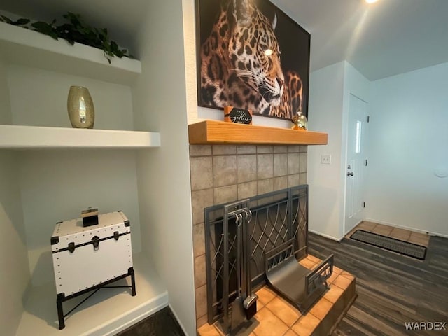 room details featuring a tiled fireplace, wood finished floors, and baseboards