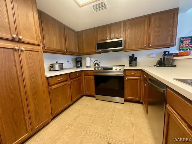 kitchen with brown cabinets, visible vents, stainless steel appliances, and light countertops