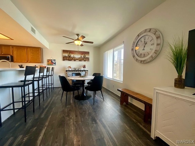 dining space with ceiling fan, visible vents, dark wood finished floors, and baseboards