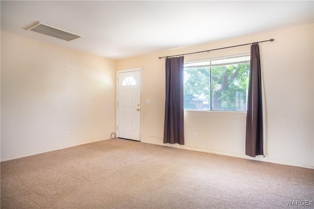 carpeted empty room with attic access and visible vents