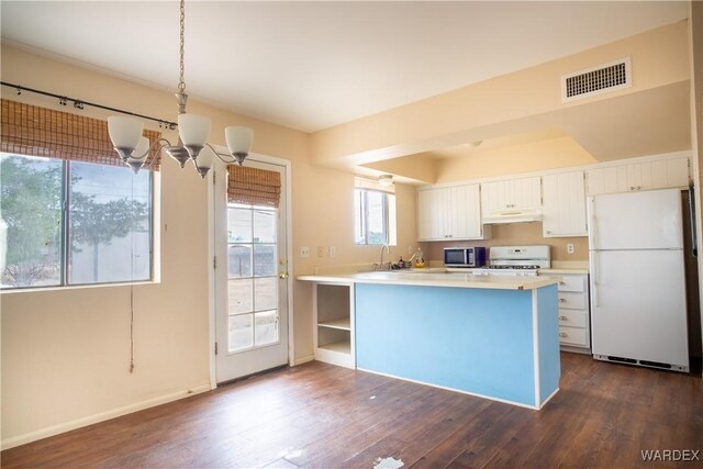 kitchen featuring a peninsula, white appliances, pendant lighting, and light countertops