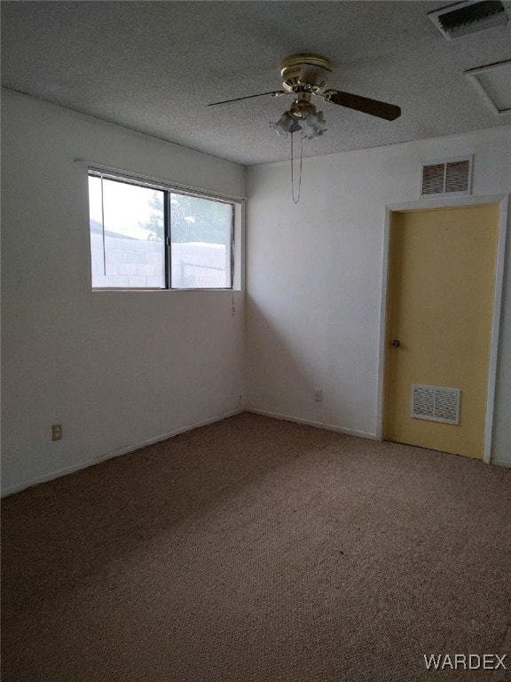 unfurnished room with a textured ceiling, carpet flooring, and visible vents