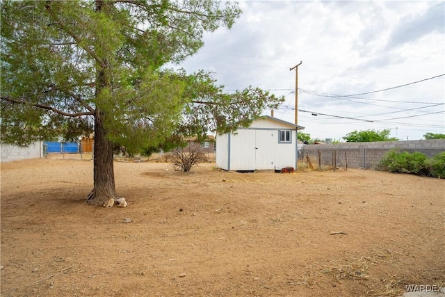 view of yard with fence, an outdoor structure, and a storage unit