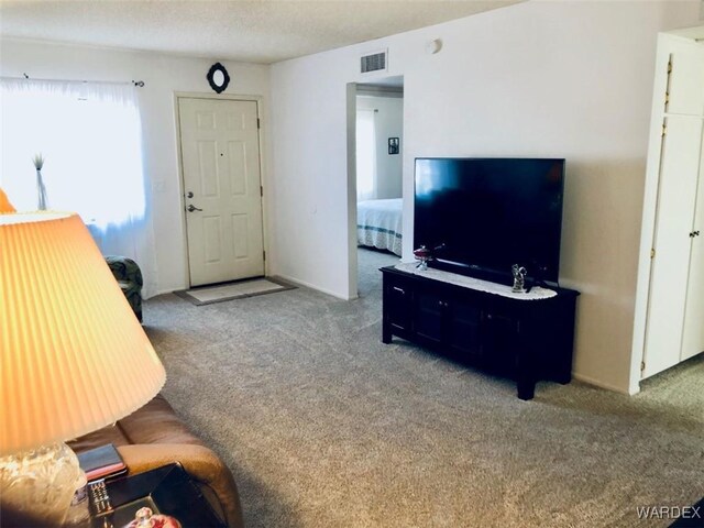 carpeted living room featuring visible vents and a textured ceiling