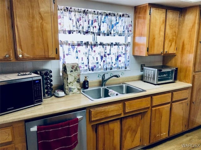 kitchen featuring black microwave, light countertops, stainless steel dishwasher, and a sink