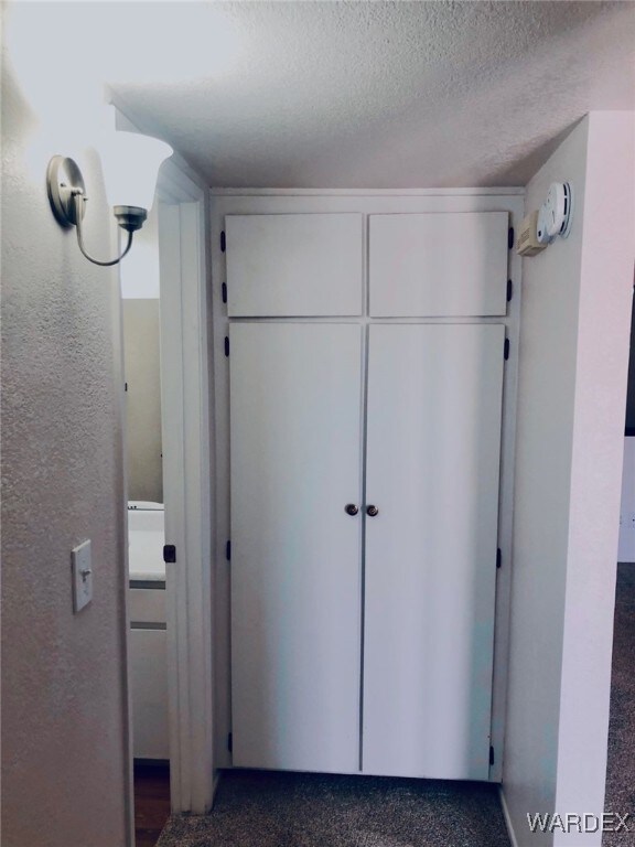 carpeted bedroom with a textured ceiling, connected bathroom, visible vents, baseboards, and a closet