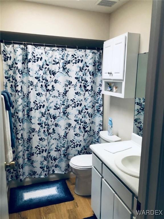 bathroom with toilet, wood finished floors, visible vents, vanity, and a shower with curtain