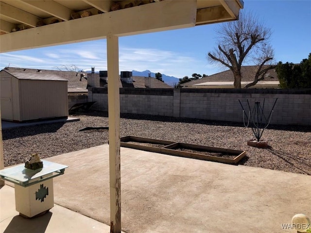 view of patio with an outbuilding, a shed, a fenced backyard, and a mountain view