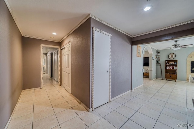 hallway with ornamental molding, arched walkways, light tile patterned flooring, and recessed lighting