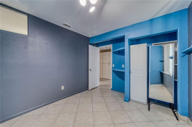 unfurnished bedroom with light tile patterned floors, baseboards, and visible vents