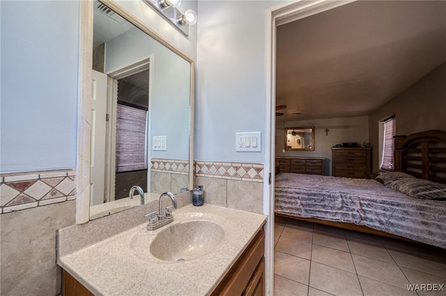 bathroom with a wainscoted wall, tile patterned flooring, tile walls, and vanity