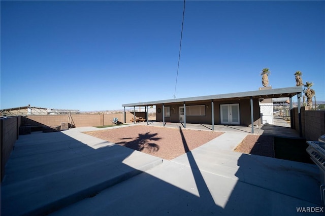 view of front of property featuring a patio area, a fenced backyard, and french doors