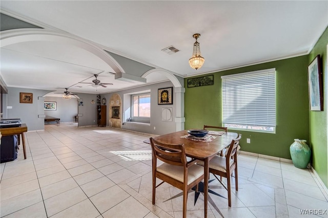 dining room featuring arched walkways, visible vents, crown molding, and light tile patterned flooring