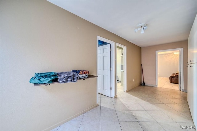 corridor with light tile patterned floors and baseboards