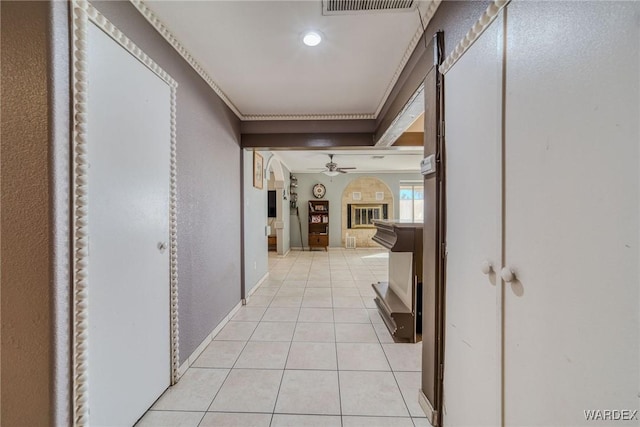 corridor featuring light tile patterned floors, baseboards, and ornamental molding