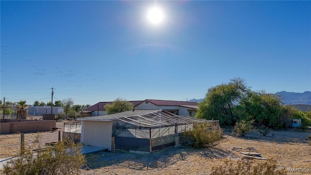 rear view of house with an outbuilding, fence, and a mountain view