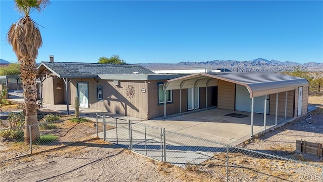 view of front of house with driveway, fence, a mountain view, and a detached carport