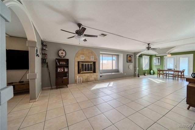 unfurnished living room with light tile patterned floors, arched walkways, visible vents, and a ceiling fan