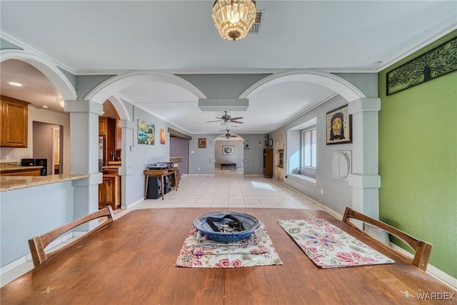 dining room featuring arched walkways, crown molding, visible vents, a ceiling fan, and baseboards