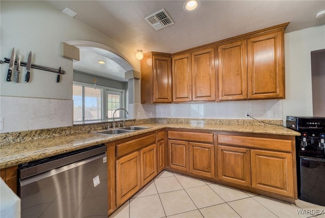 kitchen with dishwasher, a sink, visible vents, and brown cabinets