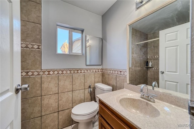 bathroom featuring tile walls, a wainscoted wall, vanity, and toilet