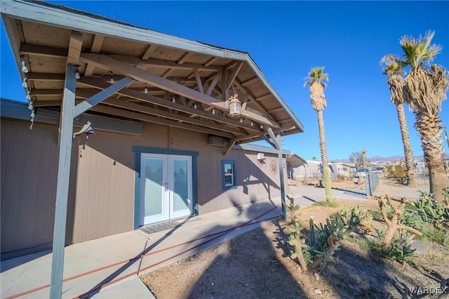 view of property exterior with french doors and fence