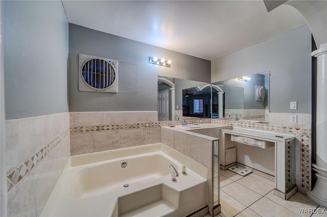 bathroom with tile walls, double vanity, tile patterned floors, a sink, and a bath