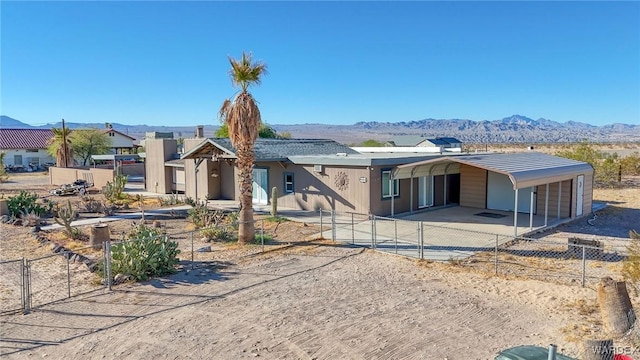 view of front of house with a carport, a mountain view, driveway, and fence