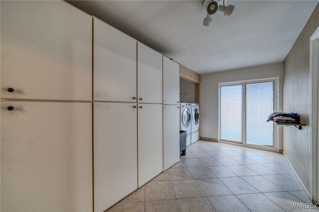 washroom featuring baseboards, cabinet space, washing machine and clothes dryer, and light tile patterned floors