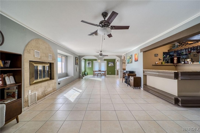 living area featuring a ceiling fan, arched walkways, visible vents, and light tile patterned floors