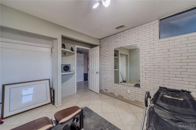 interior space with brick wall, visible vents, and tile patterned floors