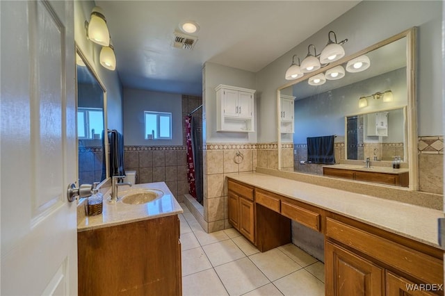 full bath featuring visible vents, wainscoting, tile patterned flooring, a shower stall, and tile walls