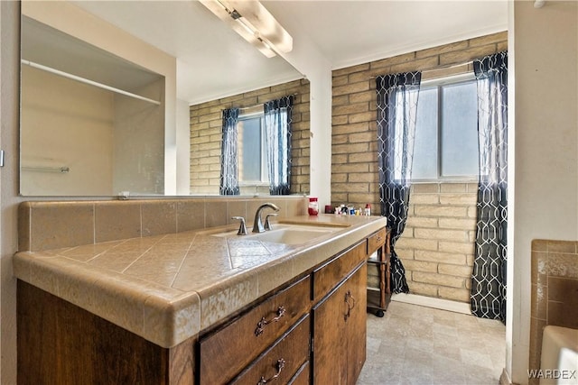 full bath featuring brick wall and vanity