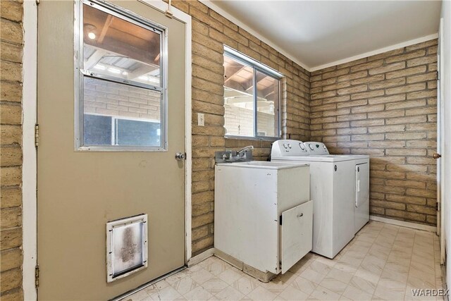 laundry area with laundry area, brick wall, and washing machine and clothes dryer