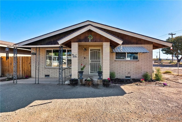 view of front of house with a patio area, crawl space, brick siding, and fence